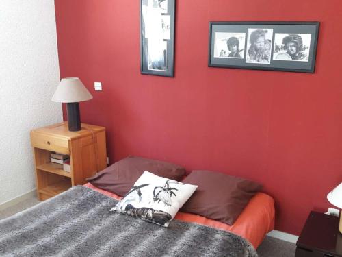 - une chambre dotée d'un mur rouge avec un lit et un miroir dans l'établissement Charmant 2 pièces 6 pers, centre Alpe d'Huez, balcon sud, prox pistes et commerces - FR-1-405-349, à Huez