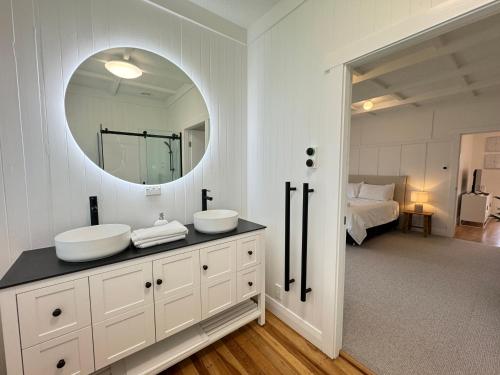 a white bathroom with two sinks and a mirror at Miami one one in Oneroa