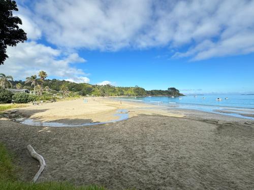 a sandy beach with people swimming in the water at Miami one one in Oneroa