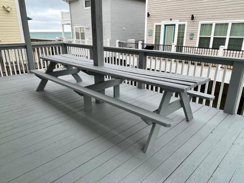 un banco de madera sentado en una terraza cerca del océano en Endless Summer Beach House, en Myrtle Beach