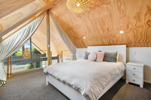a bedroom with a white bed and a wooden ceiling at The Cabin - Wellington Holiday Home in Wellington