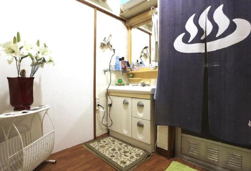 uma casa de banho com um lavatório e uma cortina de chuveiro em HILDA INN em Kashiwa