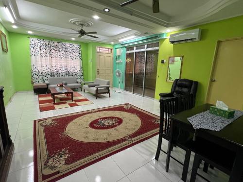 salon z zielonymi ścianami, stołem i krzesłami w obiekcie Al-Ahsan Homestay w mieście Pasir Gudang