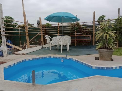 uma piscina com uma mesa e cadeiras e um guarda-sol em RENOVADA cabaña de campo y mar RELAJATE y disfruta el OTOÑO EN FAMILIA em Mala