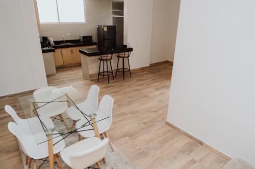 Habitación con sillas blancas y mesa de cristal. en Big Comfort Apartment en Valledupar