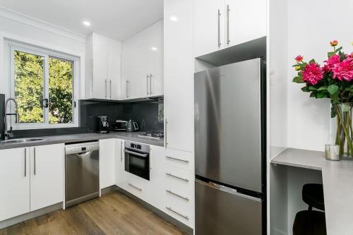 a kitchen with white cabinets and a stainless steel refrigerator at Studio Apartment in the heart of Newtown NMORE in Sydney