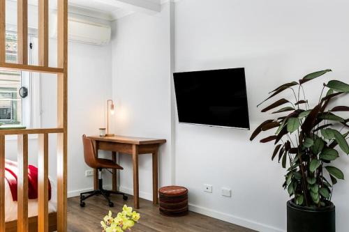 a bedroom with a desk and a television on a wall at Studio Apartment in the heart of Newtown NMORE in Sydney