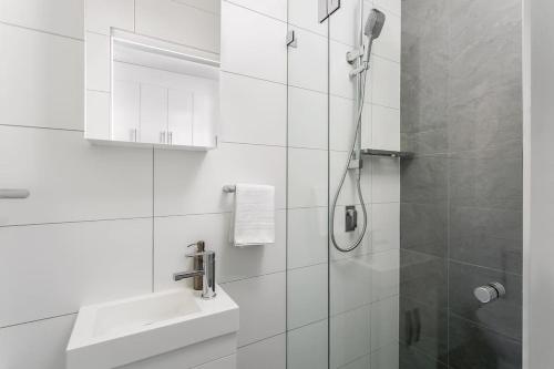 a white bathroom with a shower and a sink at Studio Apartment in the heart of Newtown NMORE in Sydney