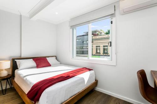 a white bedroom with a bed and a window at Studio Apartment in the heart of Newtown NMORE in Sydney