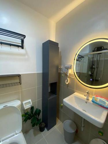 a bathroom with a sink and a toilet and a mirror at Serene Skyline Escape Las Pinas in Manila