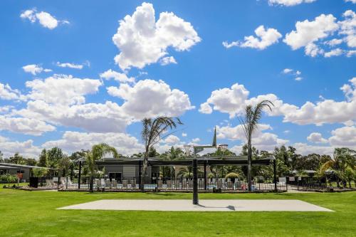 a park with palm trees in front of a building at Discovery Parks - Moama Waters in Moama