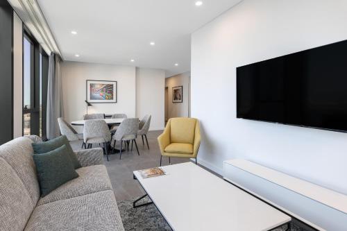a living room with a couch and a flat screen tv at Meriton Suites Melbourne in Melbourne