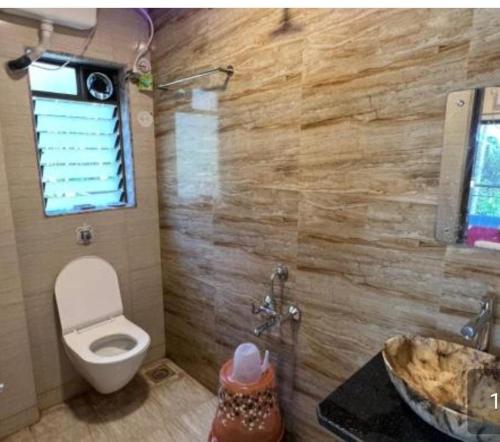 ein Bad mit einem WC, einem Fenster und einem Waschbecken in der Unterkunft SILVER SAND NAGAON in Alībāg