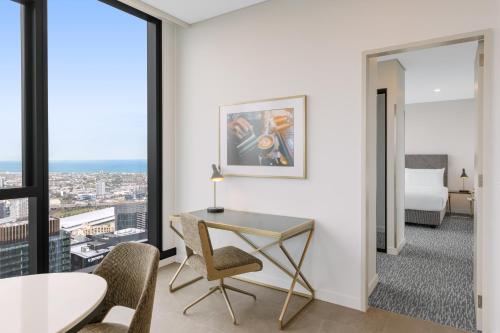 a hotel room with a desk and chair and a bed at Meriton Suites Melbourne in Melbourne