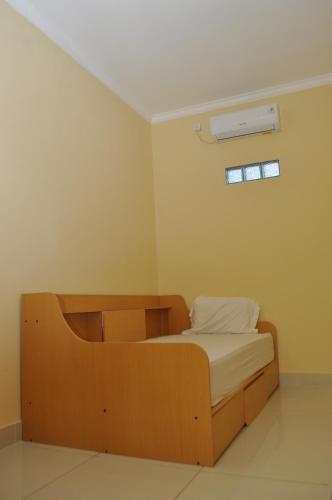 a bedroom with a wooden bed and a window at The Swarna Hotel Bayah Lebak in Muaramadur