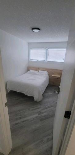 a bedroom with a white bed and a window at Cozy in Regina