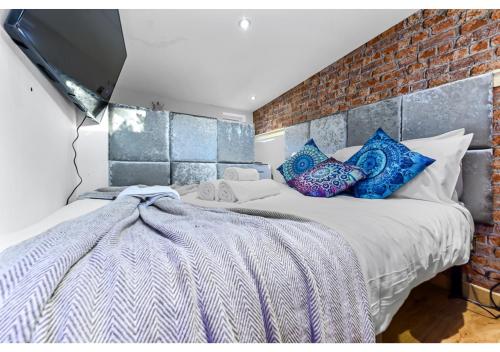 a bedroom with a bed and a brick wall at Charming Log Cabin with Hot Tub & Grill in London