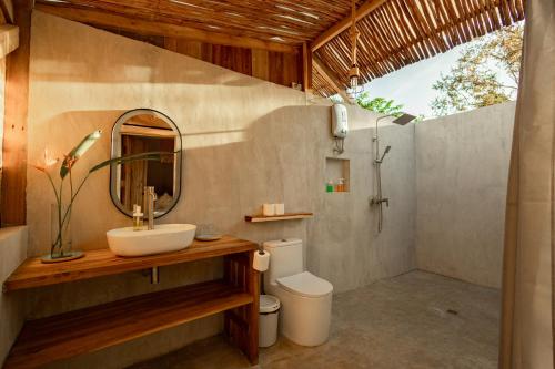 a bathroom with a sink and a toilet and a mirror at Domes and Dreams Lio Glamping in El Nido