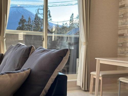 a couch with pillows in front of a window at 71 Mt view - A棟 - in Fujikawaguchiko