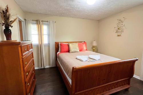 Schlafzimmer mit einem Bett mit roten Kissen und einer Kommode in der Unterkunft Foundation Paradise in Fayetteville