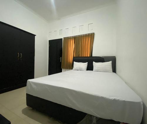 a bedroom with a large white bed with two pillows at OYO Life 93255 Kosan Teratai Jaya in Tanjung