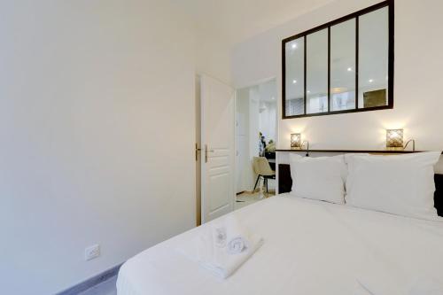 una camera da letto con un grande letto bianco con una grande finestra di Comfortable apartment Marx Dormoy a Parigi