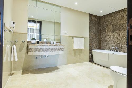 a bathroom with a tub and a sink and a toilet at Stella Stays Olaya Tower 1 in Riyadh