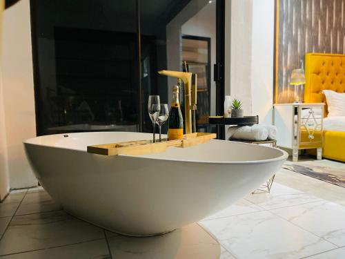 a white bath tub with wine glasses and wine bottles at 24 On Basil Boutique Luxury hotel in Johannesburg