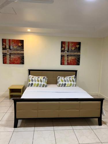 uma cama num quarto com duas pinturas na parede em Mikocheni smart apartment em Dar es Salaam