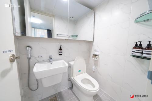 Baño blanco con aseo y lavamanos en Eunhasu D&M Residence Haetsal 1 en Daejeon