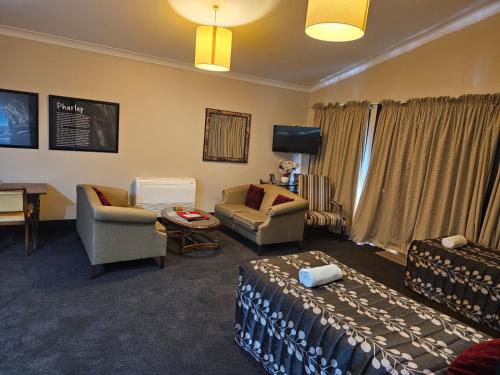 a room with a living room with a couch and a chair at Gateway Motor Inn in Masterton