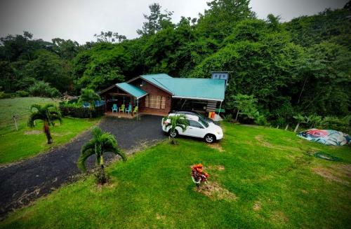a house with a car parked in front of it at Cabaña Río Blanco Guapiles Costa Rica in Guápiles