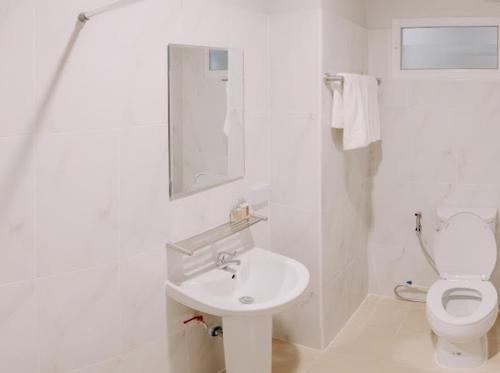a white bathroom with a sink and a toilet at Pipp Residence in Bangkok