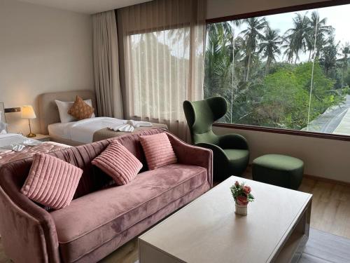 a living room with a couch and a bed and a window at The Willow Phangan in Koh Phangan