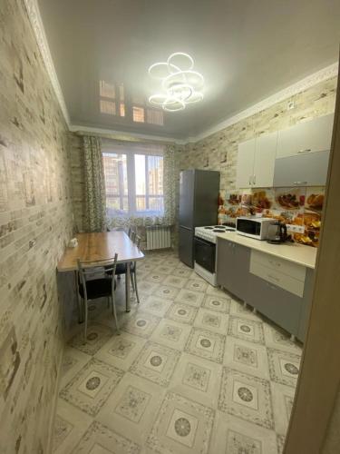 een keuken met een houten tafel en een tafel en een keuken met een aanrecht bij Уютная однушка в новостройке in Karagandy