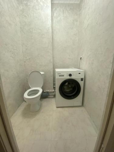 een badkamer met een toilet en een wasmachine bij Уютная однушка в новостройке in Karagandy