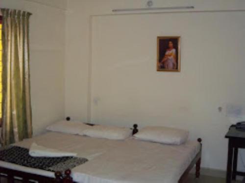 two beds in a room with a picture on the wall at Sap Inn Pallom in Kottayam