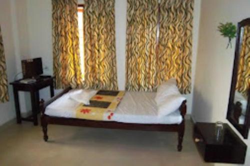 a bed in a room with curtains and a window at Sap Inn Pallom in Kottayam