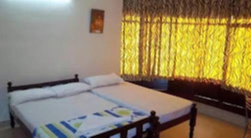 a bedroom with a bed and a yellow curtain at Sap Inn Pallom in Kottayam
