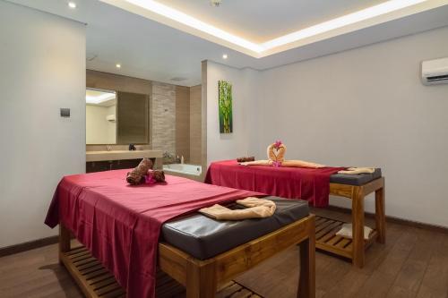a bathroom with two beds with red sheets and a sink at Best Western Kamala Jimbaran in Jimbaran