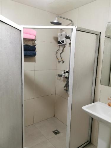 een douche met een glazen deur naast een wastafel bij Unit 402, Cedar Peak in Baguio