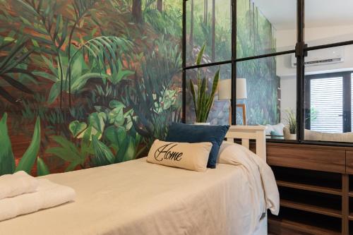 1 dormitorio con 1 cama con un mural tropical en la pared en Fliphaus Ravignani 2200 'B' - 3 Bd Vintage Palermo en Buenos Aires