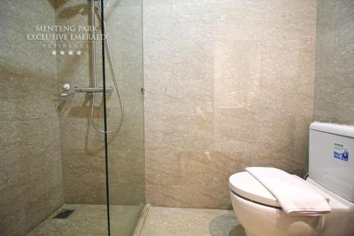 a bathroom with a toilet and a glass shower at Menteng Park Exclusive Emerald in Jakarta