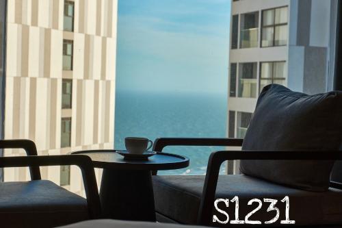 a coffee cup sitting on a table in front of a window at Apec MANDALA CHAM BAY MUI NE SPA RESORT AND CONDOTEL in Ấp Thiẹn Ái
