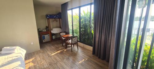 1 dormitorio con balcón con 1 cama y 1 mesa en Riverfront villa & pool kampot, en Kampot