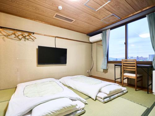 two beds in a room with a tv and a desk at Okasan Hotel - Vacation STAY 77675v in Ogaki