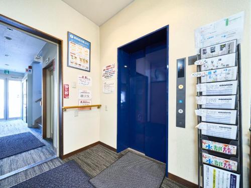 um corredor com uma porta azul e placas na parede em Okasan Hotel - Vacation STAY 77675v em Ogaki