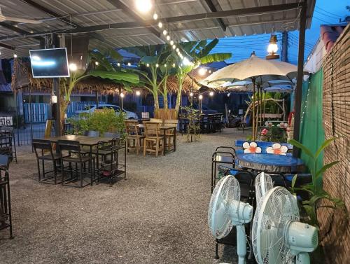 a patio with tables and chairs and a tv at ครัวบ้านเอื้อ ห้องพักรายวัน in Ban Thung Sawang
