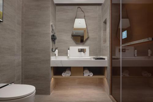 bagno con servizi igienici, lavandino e specchio di Wanda Yue Suzhou Huangdai a Suzhou