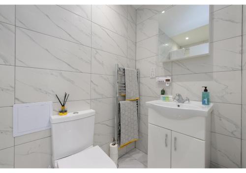 La salle de bains blanche est pourvue de toilettes et d'un lavabo. dans l'établissement Splendid and Comfy 1 bedroom apartment, à Londres